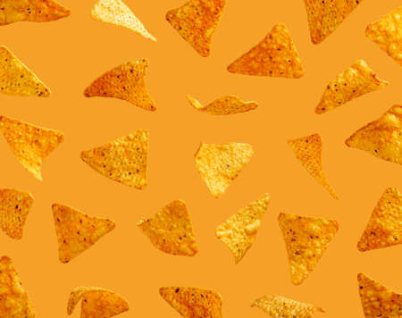 Nachos corn chips flying in the air on orange backgroundの写真素材