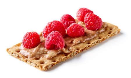 Healthy rye crispbread with cream cheese, chocolate cream, banana and raspberries isolated on white backgroundの写真素材
