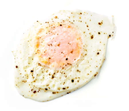 Over easy baked egg with pepper isolated on white background, top viewの写真素材