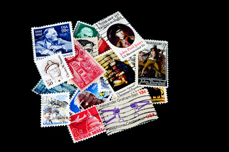 A pile of assorted USA postage stamps isolated against a black backgroundの写真素材