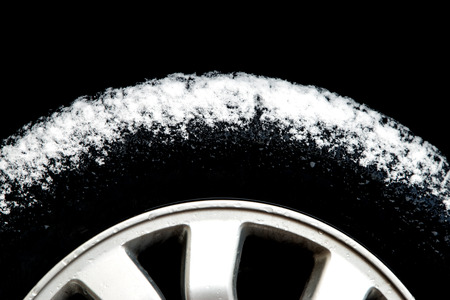 Car Tyre with melting snow against a black backgroundの写真素材