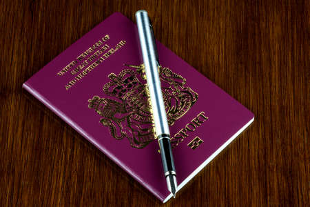 Passport and fountain pen on a old varnished wood table topの写真素材