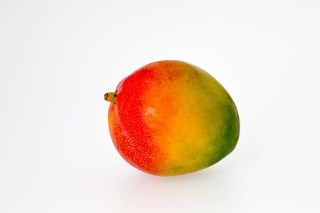 A brightly colored whole mango fruit isolated on white background  Isolated on white background の写真素材