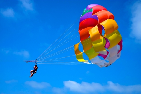 A parachute being towed at sea with a clear blue sky in the background.