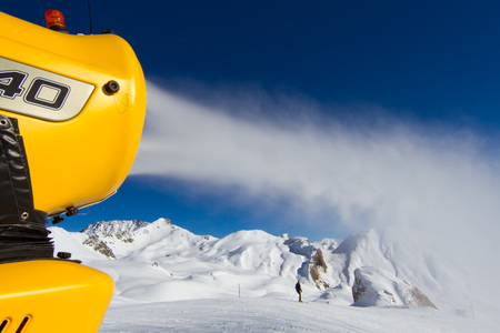 Snow cannon spraying out fake snow on ski slope.の写真素材