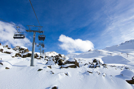 Chairlift hovering above snowcovered rocks at ski resort.の写真素材