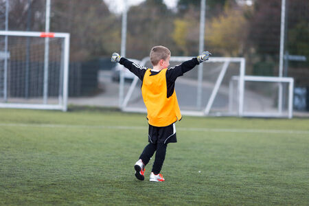 Young goal keeper celebrating a goal scored by his team.の写真素材