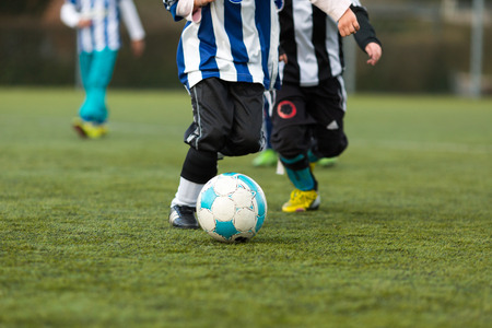 Close-up of soccer ball andlegs of two boys playing soccer. Trademarks have been removed.の写真素材