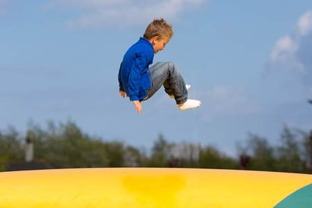 Boy jumping up and down on bouncy pad. Trademarks have been removed.の写真素材