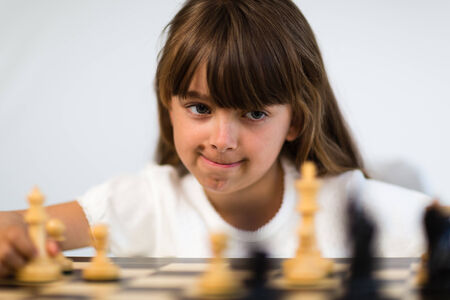 Young caucasian girl with long hair playing a game of chess.の写真素材