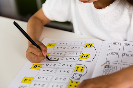 Young caucasian girl doing her homework while sitting at table.の写真素材