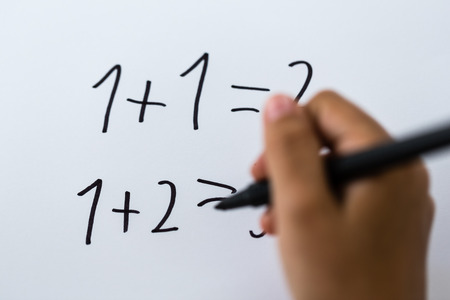 Close-up of simple math written on white piece of paper.の写真素材