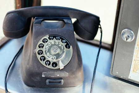 Traditional and very worn rotary phone in phone booth.の写真素材