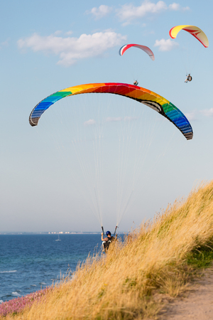 Multiple paragliders with their parachutes on a sunny day.の写真素材