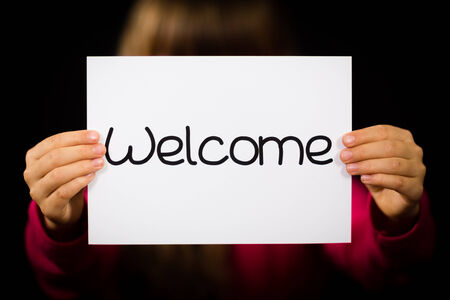 Studio shot of child holding a Welcome sign made of white paper with handwriting.の写真素材
