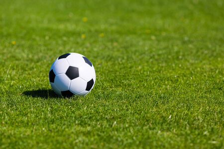 Black and white soccer ball on green soccer pitch.の写真素材