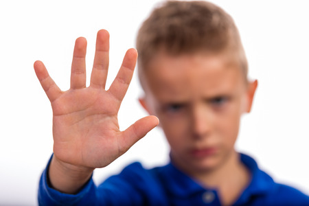 Young boy making stop gesture with his hand. Focus is on the hand. The face of the boy is blurred.の写真素材