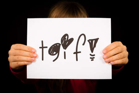 Studio shot of child holding a TGIF Thank God It is Friday sign made of white paper with handwriting.の写真素材