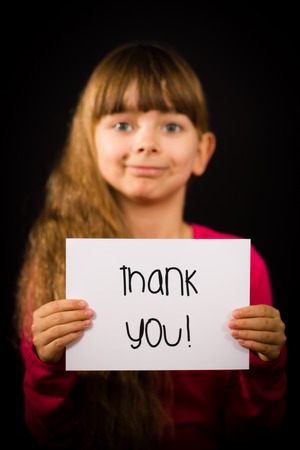 Studio shot of child holding a Thank You sign made of white paper with handwriting.の写真素材