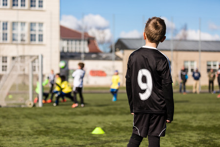 Blur of young kids playing a youth soccer match outdoors on an green soccer pitch.の写真素材
