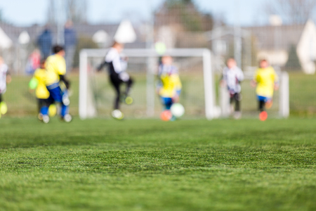 Blur of young kids playing a youth soccer match outdoors on an green soccer pitch.の写真素材