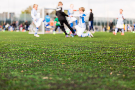 Shallow depth of field shot of young boys playing a kids soccer match on green turf.の写真素材