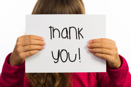 Studio shot of child holding a Thank You sign made of white paper with handwriting.の写真素材