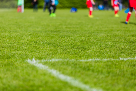 Shallow depth of field shot of young boys playing a kids soccer match on green grass.の写真素材