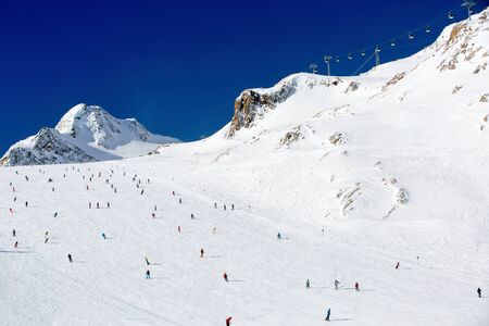 Scattered groups of skiers descend a wide ski run at the Tiefenbach glacier at the Austrian ski resort Soelden.の写真素材