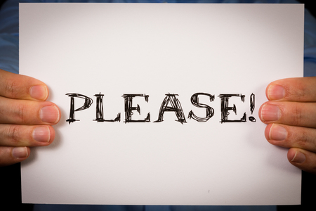 Studio shot of man holding white sign with the word Pleaseの写真素材
