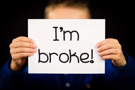 Studio shot of child holding an I am Broke sign made of white paper with handwriting.の写真素材