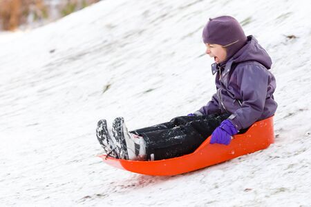 Young girl playing with sleigh in the snow on winter day.の写真素材
