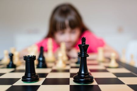 Young white child playing a game of chess on large chess board.の写真素材