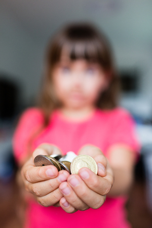 Blur of young girl holding a collection of coins in her hands.の写真素材