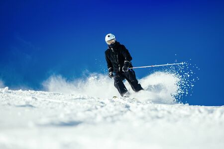 Male skier skiing in fresh snow on ski slope on a sunny winter day at the ski resort Soelden in Austria.の写真素材