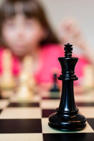 Young white child playing a game of chess on large chess board.