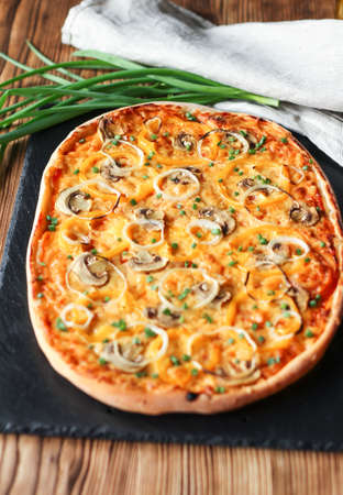 Vegeterian home made pizza with yellow pepper and mushrooms, onion, tomatoes on wooden tableの写真素材