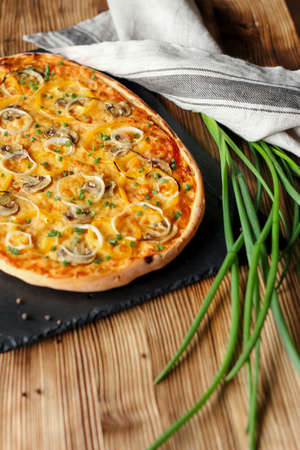 Vegeterian home made pizza with yellow pepper and mushrooms, onion, tomatoes on wooden tableの写真素材