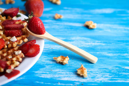 Waffles with strawberry and nuts on white plate on blue background.の写真素材