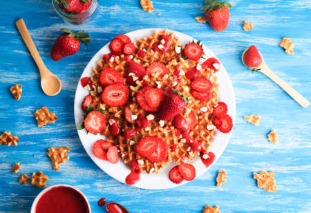 Waffles with strawberry on white plate on blue background. Top view. Flat lay.の写真素材
