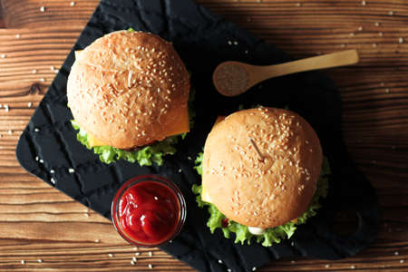 Two handmade burgers with beef, salad and cheese on wooden brown table. Buns with sesame seedsの写真素材