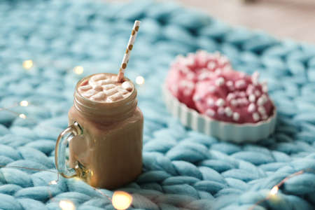 Pink donut with marshmallow and hot chocolate in cup on blue merino knit blanket. Lights on backgroundの写真素材