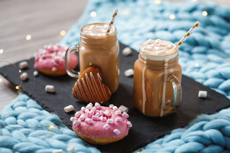 Pink donut with marshmallow and hot chocolate in cup on blue merino knit blanket.の写真素材