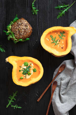 Half pumpkin with soup on black background. Flat lay. Vertical composition.の写真素材