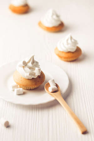 Cupcakes with vanilla cream on white wooden backdrop. Vertical compositionの写真素材