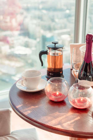 Romantic dinner. Burning candles. Tea and cups on the table on city backgroundの写真素材