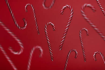 Falling candy canes on red background. Candies levitation christmas trendy patternの写真素材