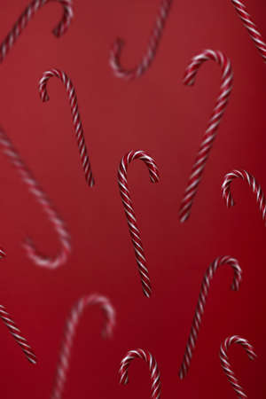 Falling candy canes on red background. Candies levitation christmas trendy patternの写真素材