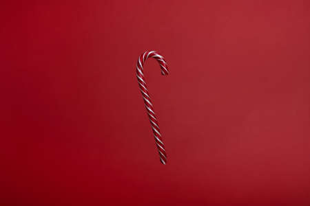One striped candy cane on red background. Cristmas lollipopの写真素材