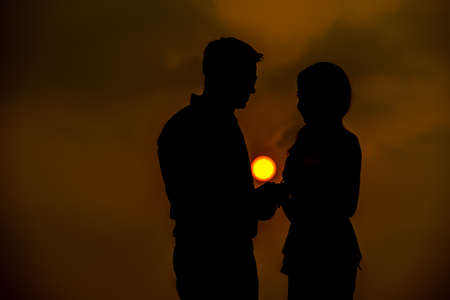 A light kiss,Romantic lovers hugging at twlilight with sunset in backgroundの写真素材